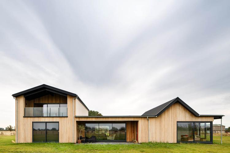 Gally's Farm – a modern, new build farm house This timber-framed bungalow with an adjacent barn was built with its environment very much in mind. Drawing inspiration from the buildings that pepper its South Cambs countryside surroundings, Gally's Farm was vertically clad in long strips of larch. Sliding barn doors were custom built and designed by Inti Construction for the barn end of the building and then were mirrored elsewhere on the house.