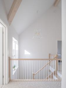 Light hits the stairs which take you on to a landing with a vaulted ceiling and exposed beams for this new build south of Cambridge.